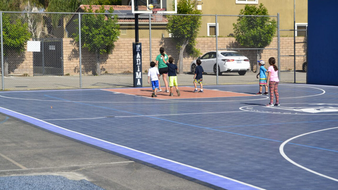 kids playing on a blue outdoor basketball court.
