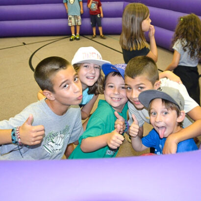 group of boys making faces and smiling for the camera in an inflatable structure.