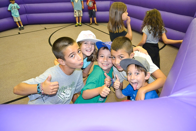 group of boys making faces and smiling for the camera in an inflatable structure.