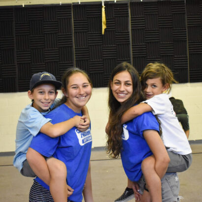 two boys given piggyback rides by camp counselors.