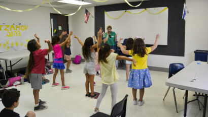 kids dancing in a classroom with a camp counselor at the front.