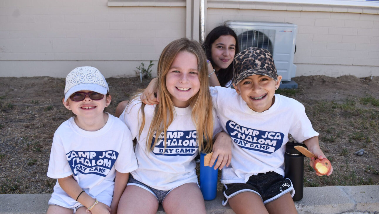 group of girls smiling and sitting on a wall.