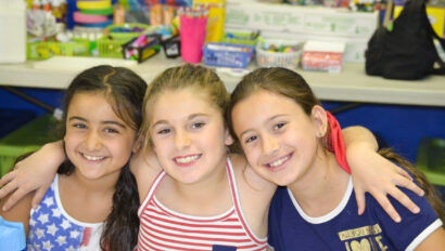 three girls sitting and smiling.