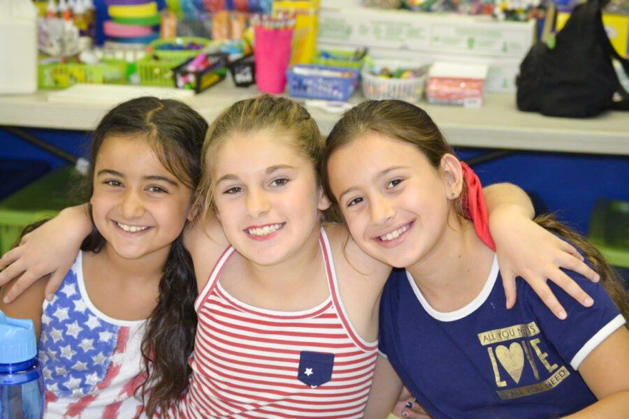 three girls sitting and smiling.