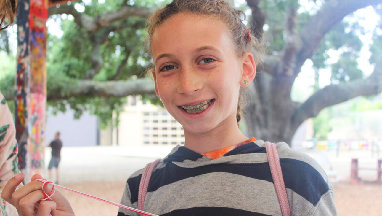 girl smiling and holding a string.