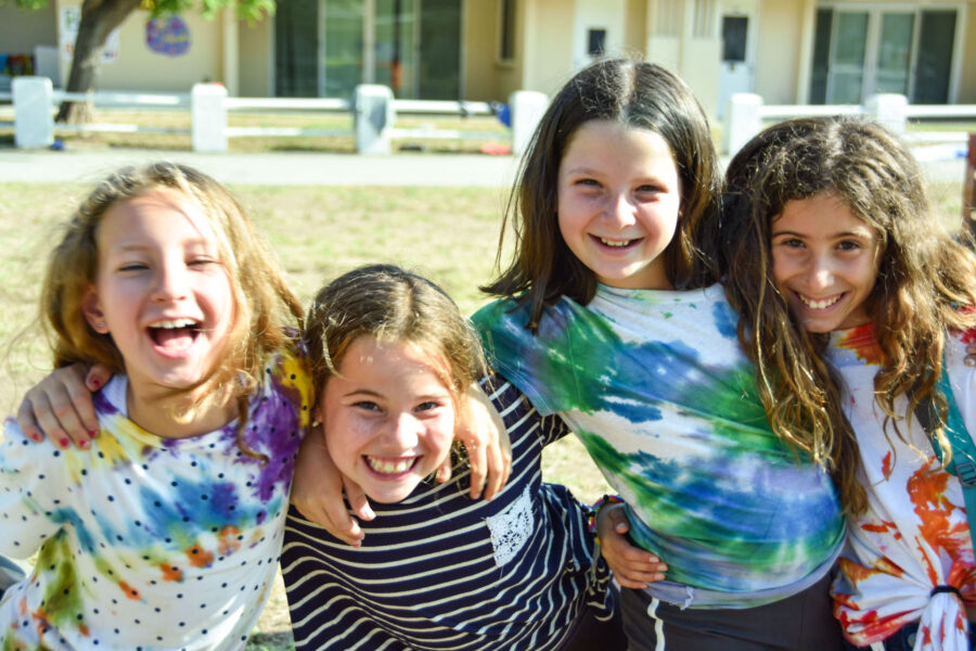 four smiling girls in tie dye shirts.