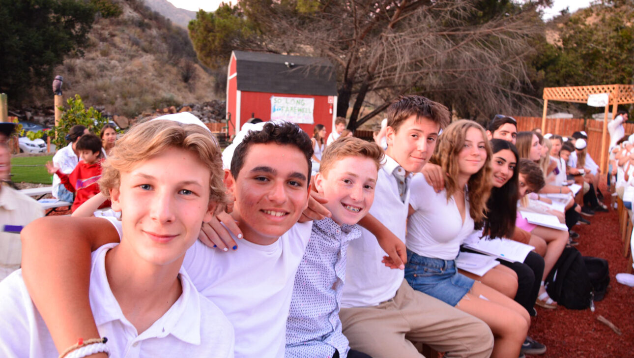 group of kids hanging on each others shoulders and smiling.