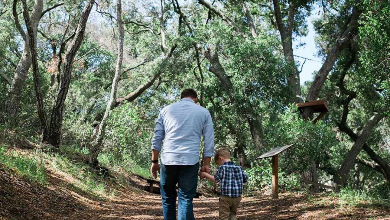 man walking in the forest with a young boy.