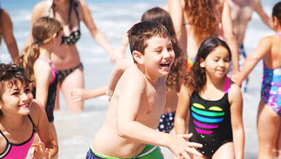 kids running in shallow water at the beach.