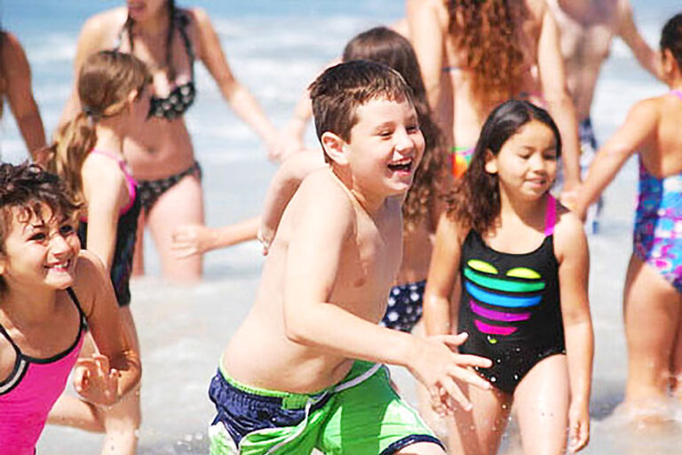 kids running in shallow water at the beach.