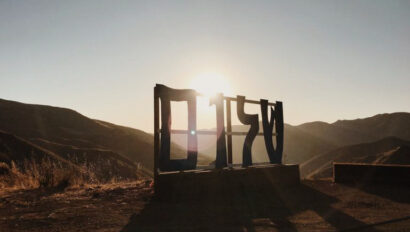 large sign on the ground with hills in the background as the sun rises.