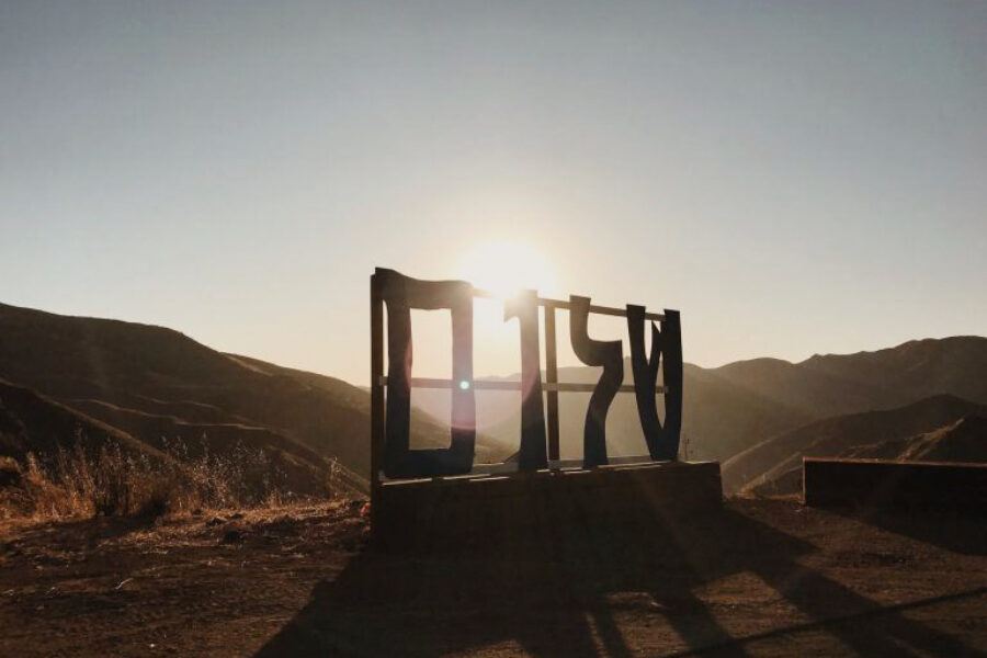 large sign on the ground with hills in the background as the sun rises.