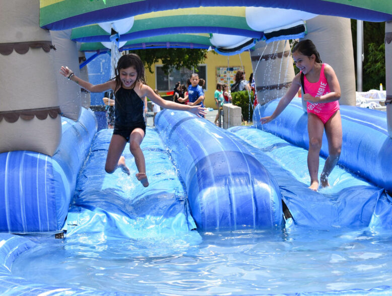 two girls running down an inflatable water slide.