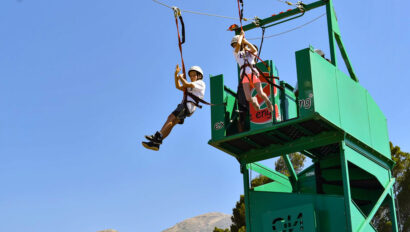 two boys jumping off a platform on a zipline.